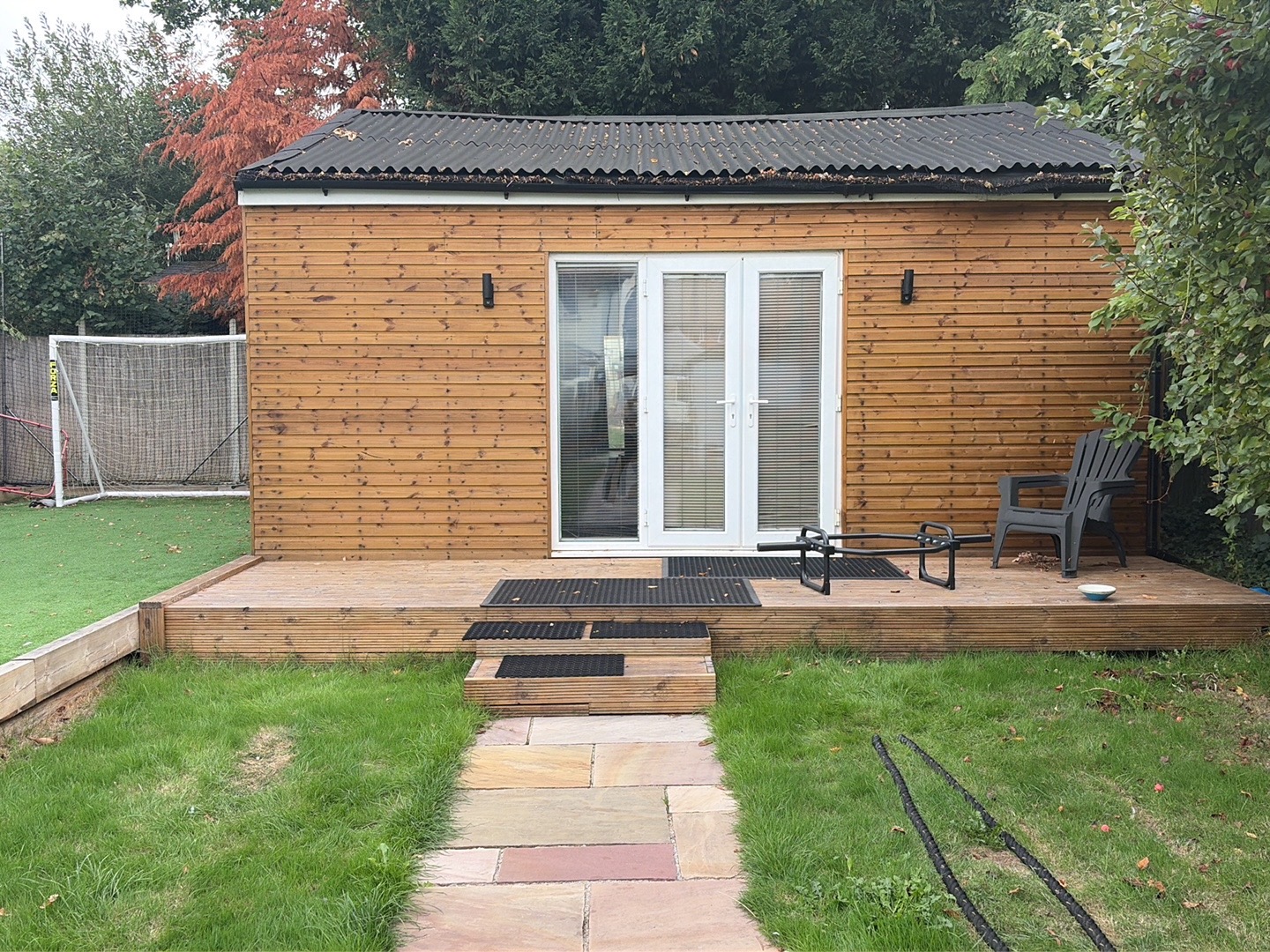The SimplyBfit garden studio: a timber building with French doors and decking across a lawn
