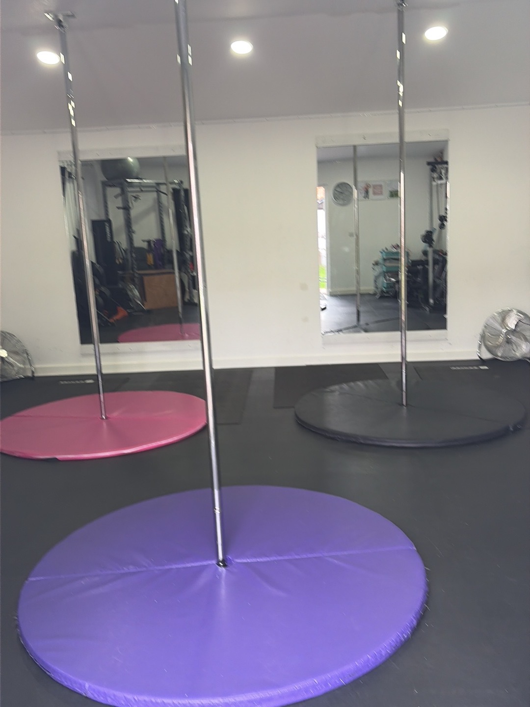 Three poles with pink, grey and purple crash mats in the studio